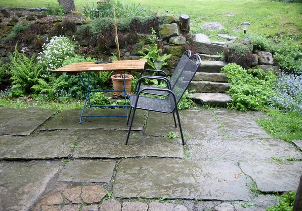 Terrace with garden furniture during heavy rain. Country garden in a mountain village.