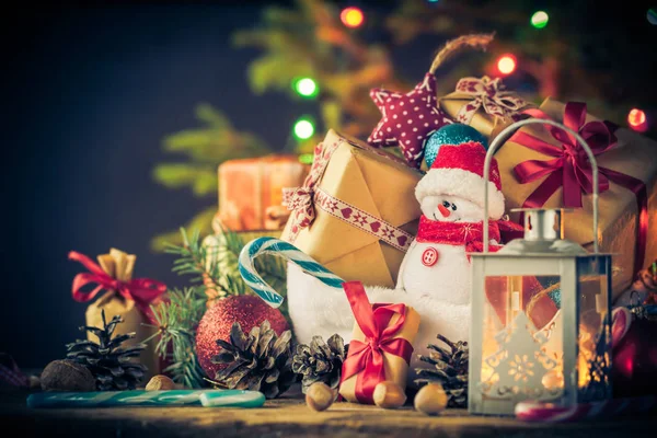 Tarjeta de Navidad muñeco de nieve adornos regalos árbol luces fondo — Foto de Stock