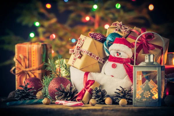 Tarjeta de Navidad muñeco de nieve adornos regalos árbol luces fondo — Foto de Stock