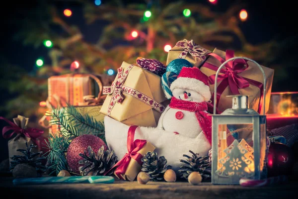 Carte de Noël Ornements bonhomme de neige cadeaux arbre lumières fond — Photo