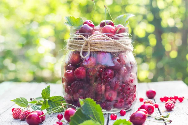 Frasco de vidro cheio de frutas cerejas e framboesas — Fotografia de Stock