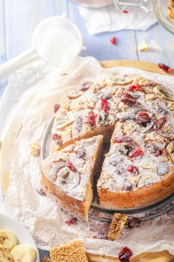 Fındık, susam ve kızılcık bir tahta üzerinde olan bir dilimlenmiş muz pasta