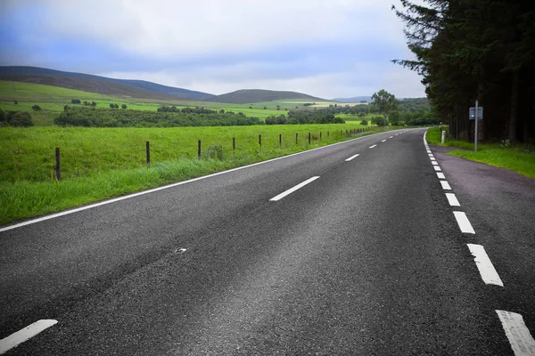 Asphalt road through the green field and clouds on blue sky — Stock Photo, Image