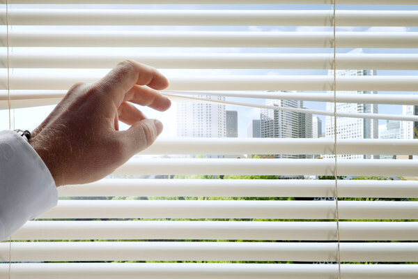 close up view of man 's head spreading blinds and sunny city background
 