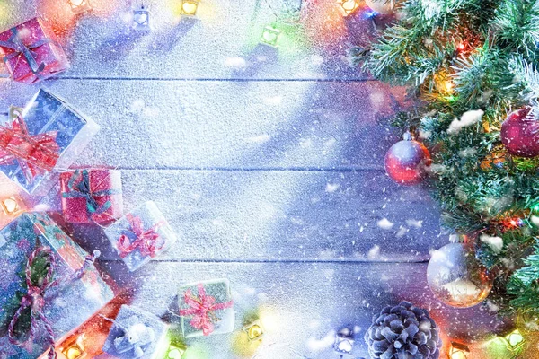 Kilátás a megvilágított karácsonyfa és az ajándékok dobozok Hófúvásából fahátfallal — Stock Fotó