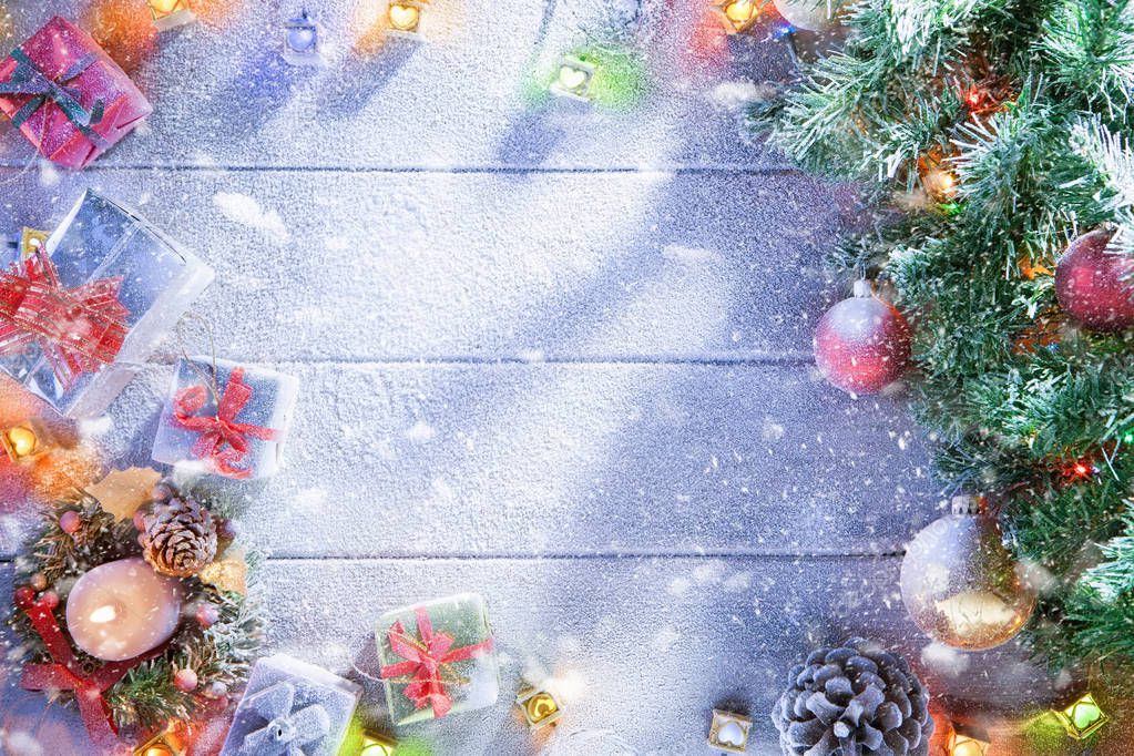 view  of lit Christmas tree  and gift boxes on snowbound  wooden back