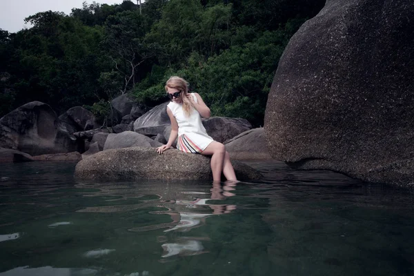 岩の上に座って、水の上の少女の肖像画 — ストック写真