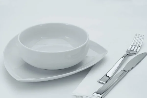 Close-up van witte platen en gebruiksvoorwerpen op witte tafel — Stockfoto