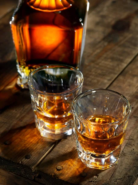 På nära håll beskåda av glas med is och whisky och en flaska åt sidan — Stockfoto