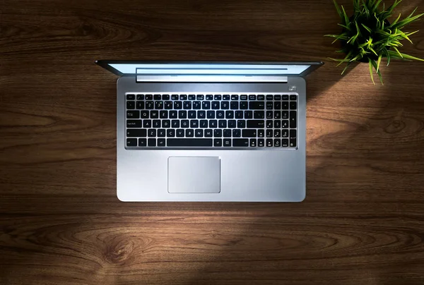 Close-up van leuke zilveren laptop op houten schrijftafel toppunt — Stockfoto