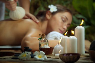 portrait of young beautiful woman in spa environment. focused on candles. clipart