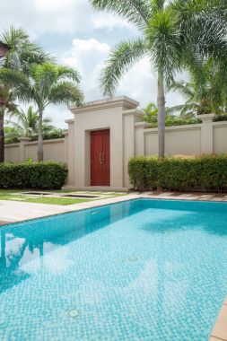 Etrafı çimen ve kiremitlerle kaplı tropik yüzme havuzu manzarası