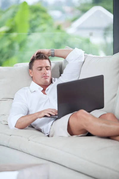 Portret młodego człowieka na kanapie z laptopem w letnim domu środowiska — Zdjęcie stockowe