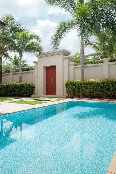 Vista della piscina in stile tropicale con erba e piastrelle intorno — Foto Stock