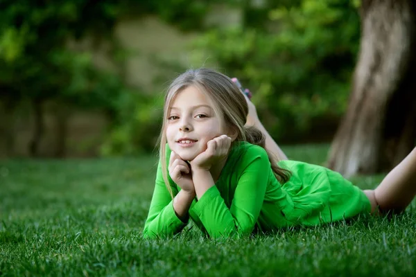 Portrait of little girl laying on the grass in summer environment — Stock Photo, Image