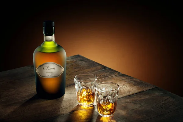 Weergave van glazen van rum en een fles opzij op kleur achtergrond. self made etiket. — Stockfoto