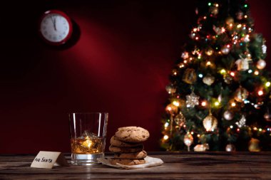 close up view of glass of whiskey with cookies on color back clipart
