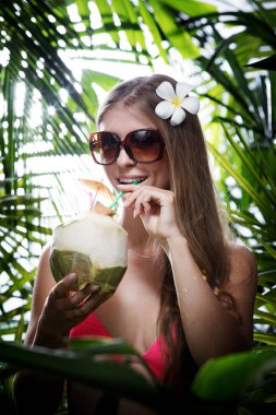 Genç bir kadının portresi tropikal bir ormanda asılı.