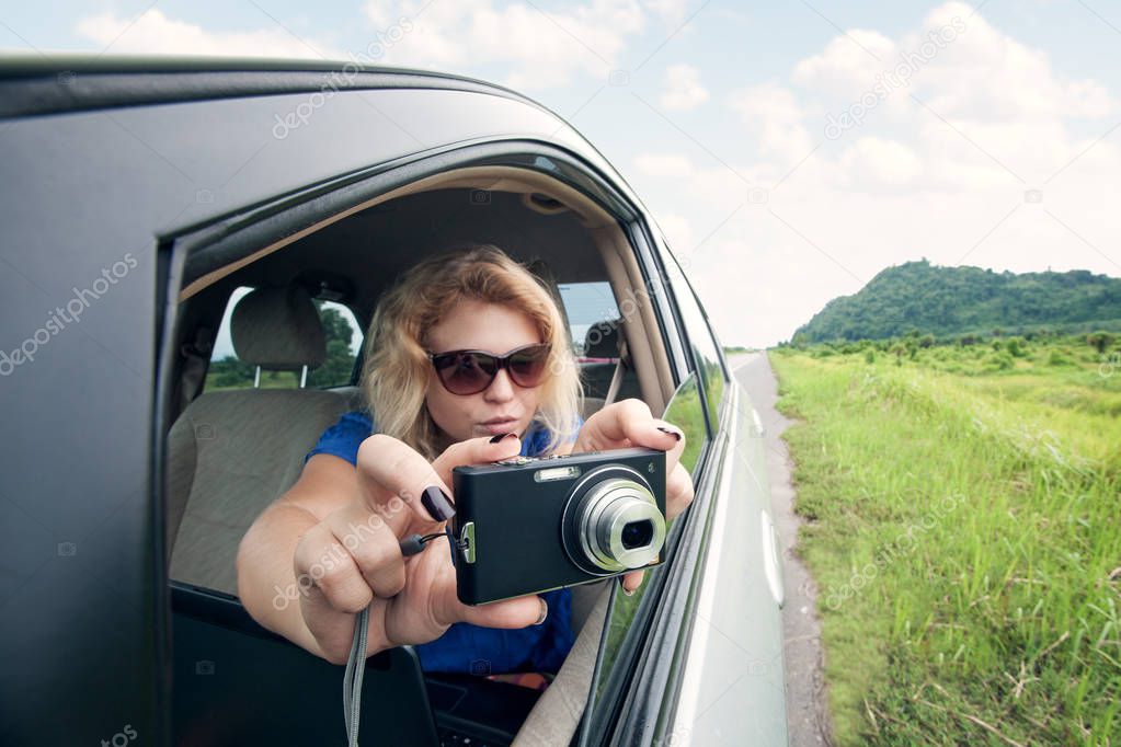 portrait of young woman taking picture from the car