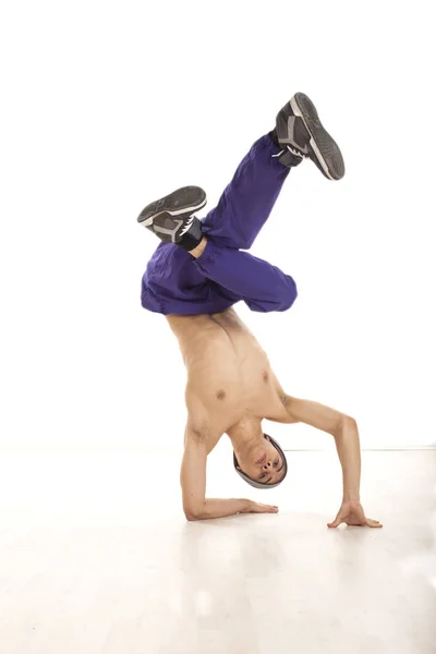 Jovem dançarino do sexo masculino sentado em mãos realizando movimento breakdance Fotografia De Stock