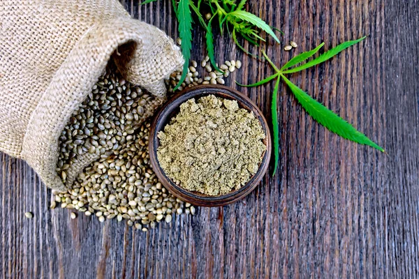 Flour hemp in bowl with grain and bag on board top — Stock fotografie