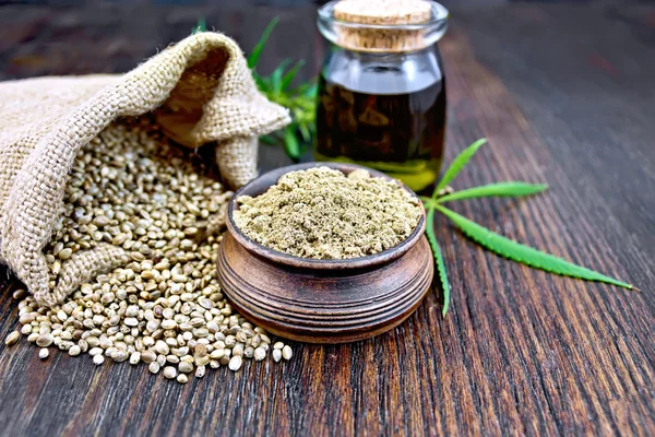 Flour hemp in bowl with leaf and oil on board — Stock fotografie