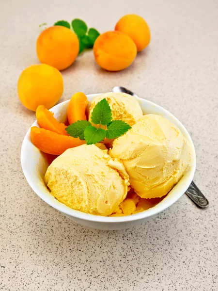 Ice cream apricot in white bowl on table with spoon — Stock fotografie