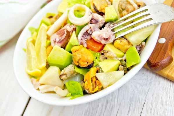 Salad with seafood and lemon in plate on white board — Stock Photo, Image