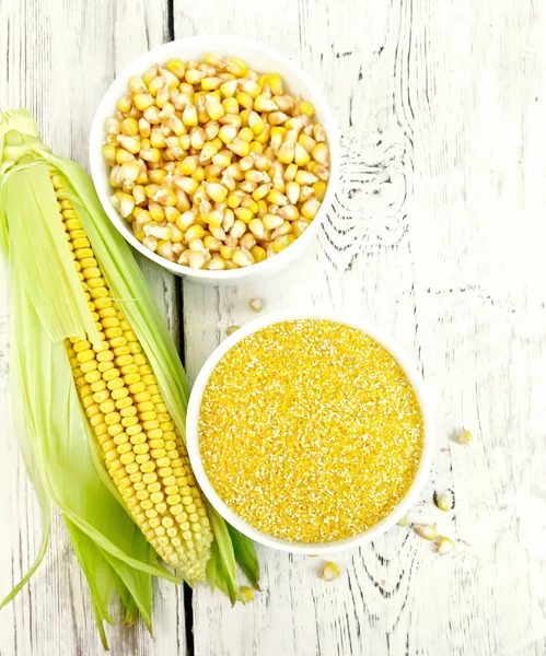 Corn grits in bowl with cobs on light board top — Stock Photo, Image