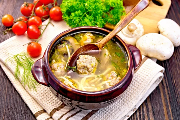 Soup with meatballs and spoon in clay bowl on napkin — Stock Photo, Image
