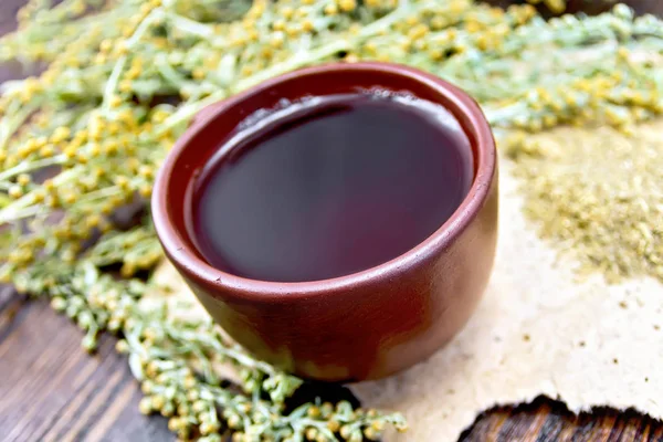 Чай с полынью в глиняной чашке на темной доске — стоковое фото