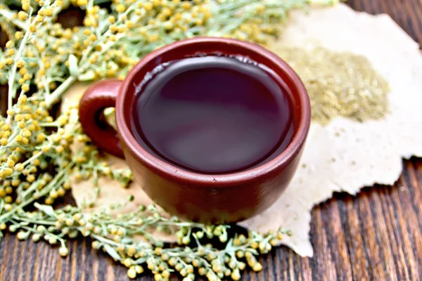 Tee mit Wermut in Tontasse auf grobem Papier — Stockfoto