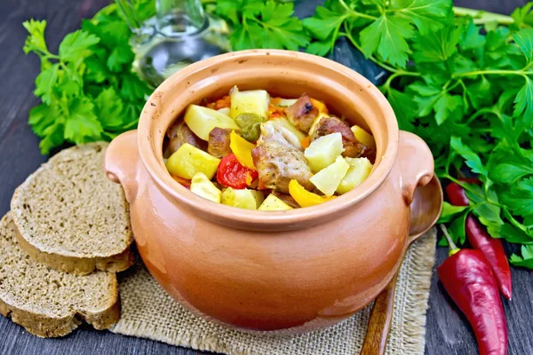 Roast meat and squash in clay pot on dark board — Stock Photo, Image