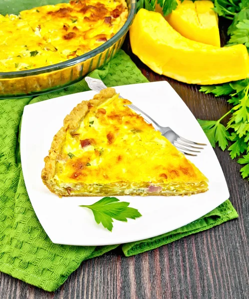 Quiche mit Kürbis und Speck im Teller auf grünem Handtuch — Stockfoto