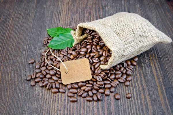 Kaffe svart korn med tagg och blad i väska ombord — Stockfoto