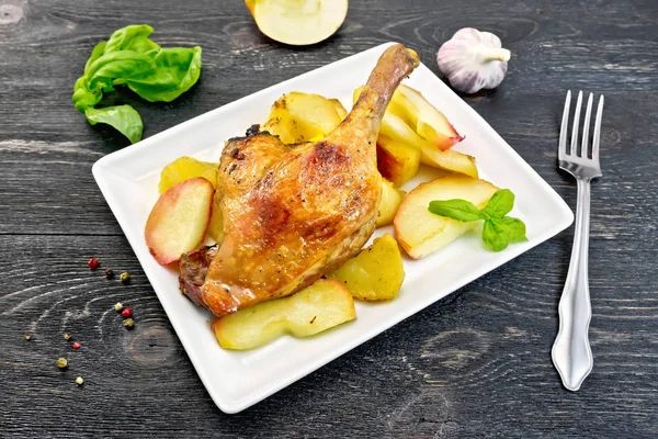 Duck leg with apple and potatoes in plate on black board — Stock Photo, Image
