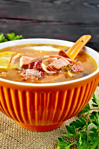 Solyanka with lemon and spoon in bowl on sackcloth — Stock Photo, Image