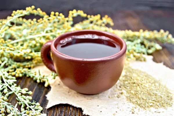 Té con ajenjo en taza marrón en la mesa —  Fotos de Stock