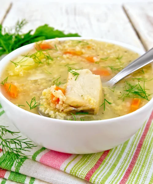 Рыба суп с просо и ложкой на белой доске — стоковое фото