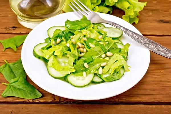 Sallad från spenat och gurka med cederträ nötter på bordet — Stockfoto