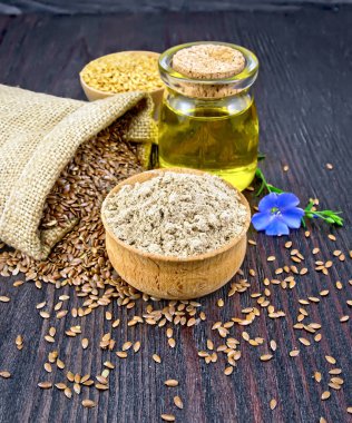 Kabın içinde keten yağı ile un ve karanlık tahtada çiçek