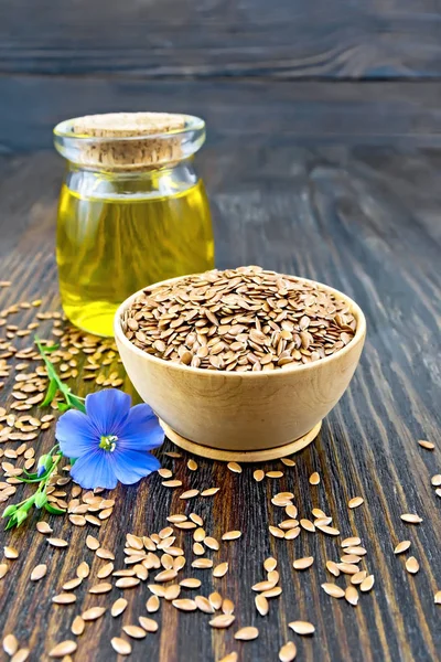 Flaxen brown seed in bowl with flower and oil on board — Stock Photo, Image