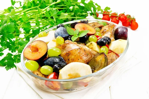 Chicken with fruits and tomatoes in pan on light wooden board — Stock Photo, Image