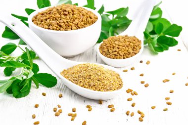 Fenugreek in two spoons and bowl with leaves on board clipart