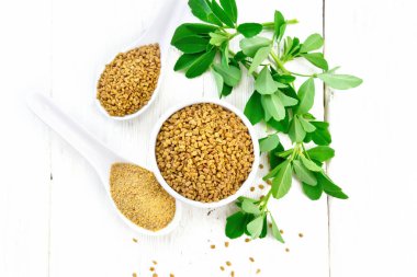Kavanozda FenuGreek ve üstünde yapraklar olan iki kaşık.