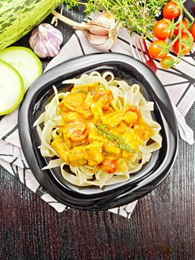 Koyu renkli tabakta gulaş olan makarna.