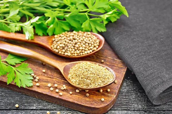 Coriander ground and seeds in two spoons on wooden board — Stock Photo, Image