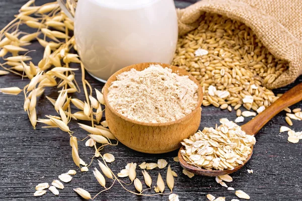 Flour oat in bowl with oatmeal on dark wooden board — Stock Photo, Image