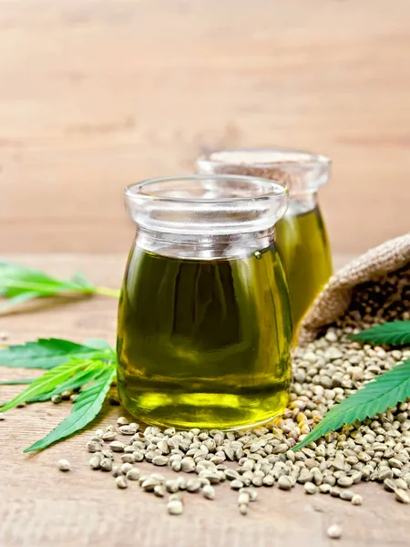 Oil hemp in two jars with sheet on board — 스톡 사진