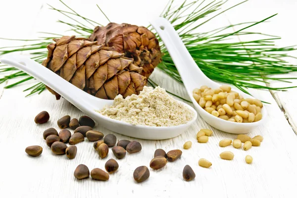 Flour cedar and nuts in two spoons on board — Stok fotoğraf